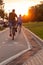 Men run and ride a bicycle along a cycle path on the embankment of Novosibirsk in the park on weekends at sunset on a warm summer