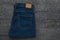 Men`s blue jeans on a dark wooden table. Classic denim clothing. Flat lay