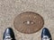 Men`s feet in blue leather sneakers near the metal hydrant hatch