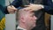 Men\'s haircut in barbershop. Close-up of master clipping a man with blond hair with scissors