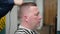 Men`s haircut in Barbershop. Close-up of master uses hair dryer and brush to finish the hair styling