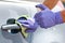 Men`s hand in protective gloves cleaning car door handle using antibacterial or cleaning solution