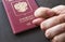 Men`s Hand shows the fico on red passport backgound. Symbol of sanctions. Negative concept. Closeup