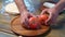 men's hands beautifully spread tomatoes on a wooden round cutting board.