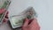 Men`s hands consider American hundred-dollar bills in the amount of one thousand dollars. Close-up. Concept. White