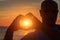 Men`s hands in the form of heart against sunlight in sunset sky, twilight time. Hands in shape of love heart, Love concept