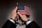 Men`s hands in handcuffs hold the American flag in their hands. Concept: American prisoner, imaginary freedom, deportation
