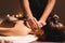 Men`s hands make a therapeutic neck massage for a girl lying on a massage couch in a massage spa with dark lighting