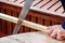 Men`s hands sawing a wooden bar with a hacksaw