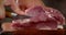 Men`s hands slice raw pork to make escalope.