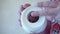 Men`s hands unwind a roll of white toilet paper