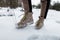 Men`s legs in stylish pants in fashionable brown winter leather shoes with yellow laces on the background of snow. Fashion. Close