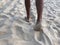 Men`s tanned legs in the white fine sand of the unique Karon beach of Phuket on the background of the sea and the Golden sunset,