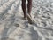 Men`s tanned legs in the white fine sand of the unique Karon beach of Phuket on the background of the sea and the Golden sunset,