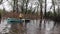 Men sail on a boat down a rural street during a flood. River flooding in spring