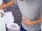 Men are standing in front of the bathroom door using their hands to hold the abdomen with severe abdominal pain or diarrhea. The c