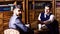 Men in suit with antique bookshelves on background.