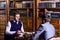 Men in suit with antique bookshelves on background.