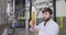 Men testing quality of fresh beer in a brewery. Brewer dressed in lab coat tasting beer from glass