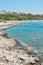 Men tourists enjoy fishing in sea blue water on rocky beach