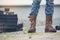 Men wear construction Boots safety footwear for worker at construction site. Engineer Wear Jeans Brown Boots Worker on Background