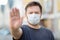 Men wearing disposable medical mask showing gesture Stop - keep social distance while coronavirus pandemic. Stay at home during
