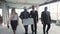 Men, woman in suit, hard hat move, communicate and discuss. Three white, one black smiling