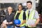 Men and woman work together, holding helmets and smile. Caucasian engineer men and black woman holding helmets in factory-