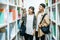 Men and women carrying a backpack and searching for books in the library