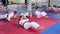 Men and women in kimono doing crunches and push-ups in gym