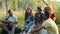 Men and women playing the guitar and singing songs in forest on summer day