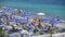 Men and women in swimwear lying in sun on seashore beach, sea waves splashing