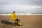 Men in yellow raincoat on the beach looking at storm.