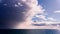 Menacing storm clouds illuminated by sunlight taking over the blue sky and pouring rain on the Pacific Ocean coastline, California