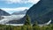 Mendenhall Glacier in Juneau Alaska. Large Glacier sliding into a lake with a waterfall beside it. Very popular tourist stop