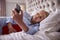 Menopausal Mature Woman Lying In Bed With Hot Water Bottle At Home Using Mobile Phone