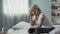 Menopause. Adult female sitting on bed and suffering from migraine, health