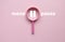 Menopause concept. Pink magnifying glass with pause symbol with a text on pink background