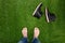 Mens feet resting on green grass with lying boots