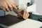 Mens hand holding a leather carving hammer and steel chisel hole punch and makes a leather wallet in his workshop