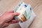 Mens hand holding white envelope full of euro bills