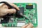 Mens hands with a soldering iron repair the TV motherboard