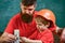 Mens work concept. Father with beard and little son in classroom teaching to use tools, chalkboard on background. Boy