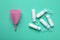 Menstrual cup and tampons on turquoise background