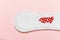 Menstrual pad with red heart glitter on pastel colored background. Minimalist still life