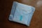 Menstrual pad wrapped in blue on wood