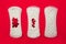 Menstrual pads with bright red glitter on red background. Woman periods cycle, menstruation frequency. Minimalist still