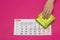 Menstrual women`s calendar and a stack of gynecological pads, female hand takes a pad, pink background, copy space, ovulation