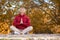 Mental balance. Adult attractive woman sits on the ground and meditating in autumn park outdoor, selective focus.