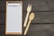 Menu clipboard, wooden fork and spoon on wooden background